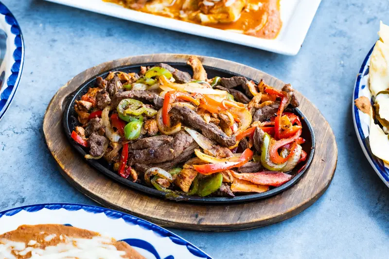 A sizzling fajita skillet on a Talavera table