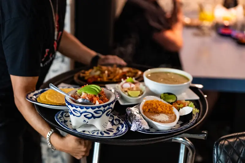 A server carrying a loaded tray at Viva Leawood