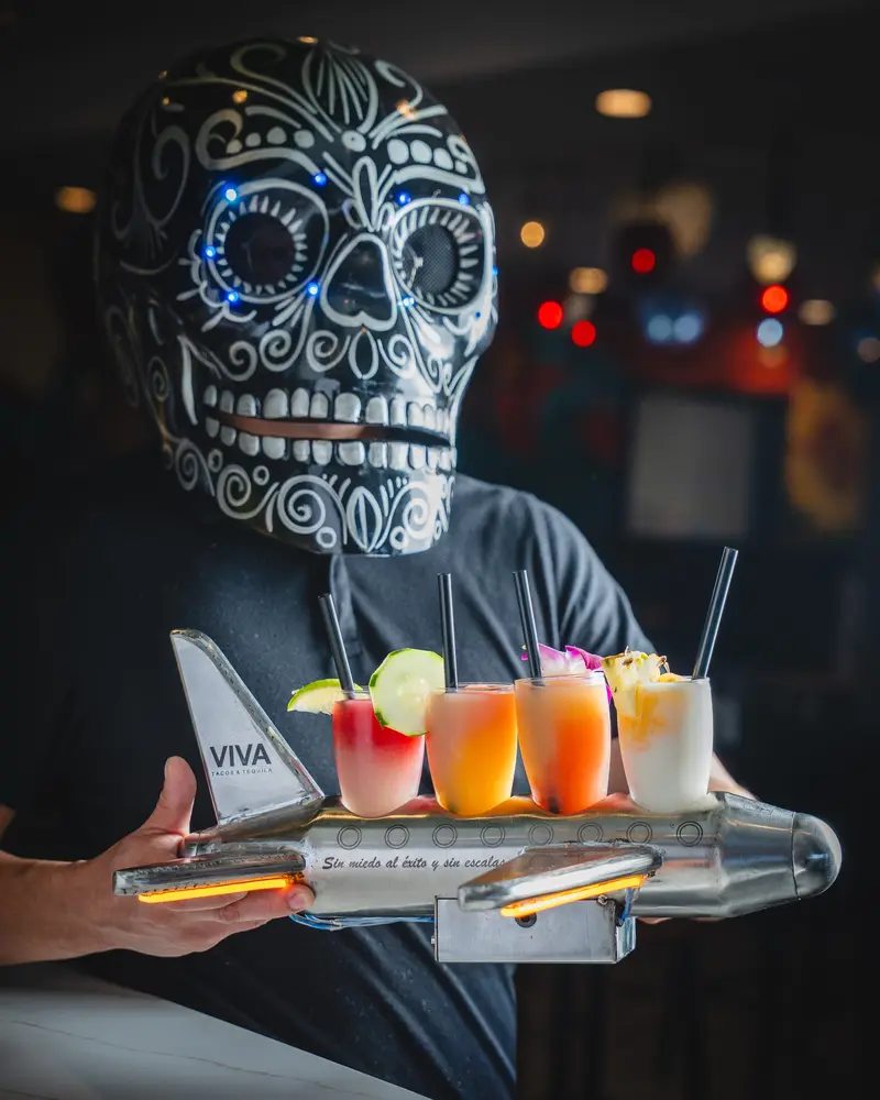 A margarita flight held up by a server in a skull mask at Viva Wichita